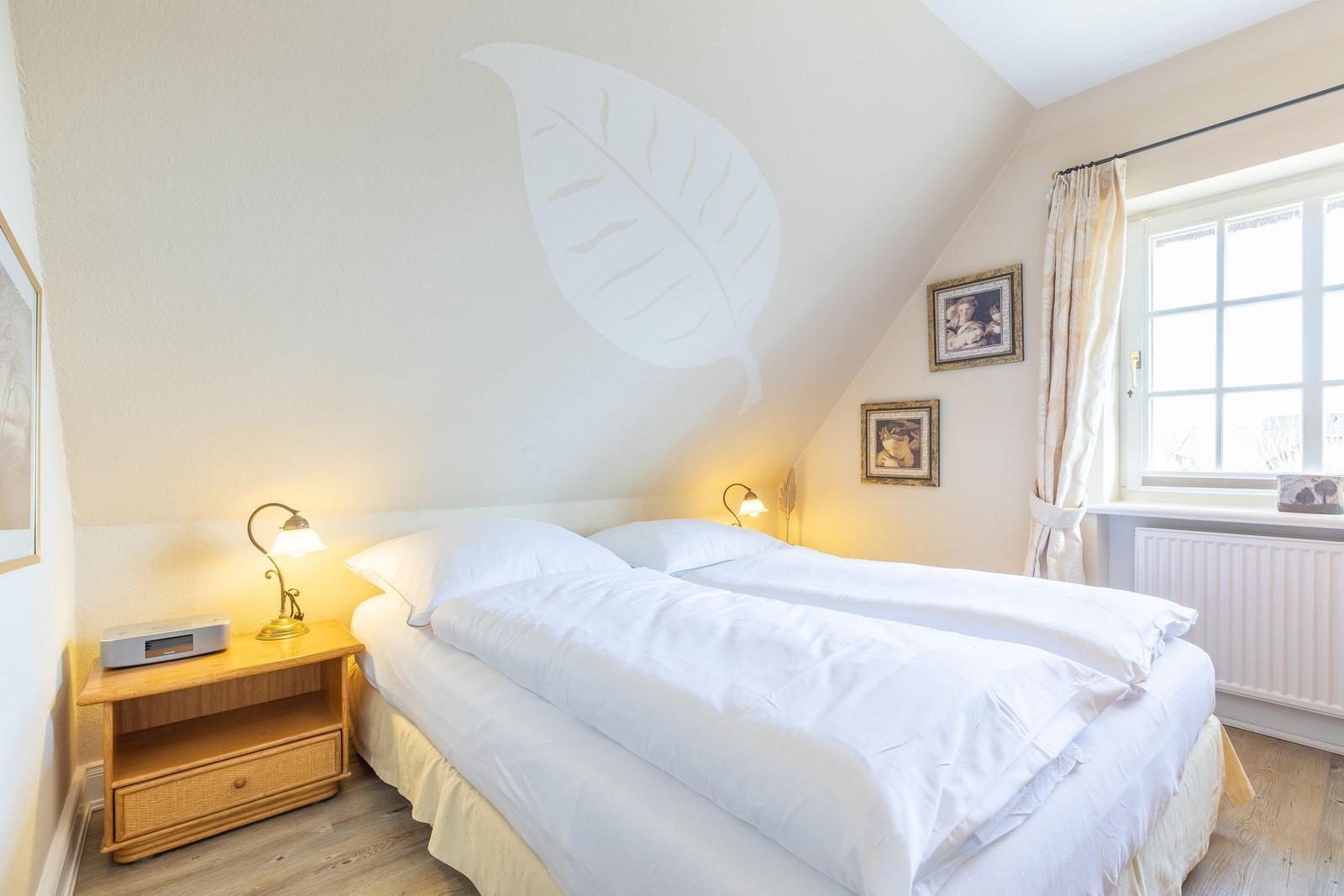 Double bed with white linens, nightstand, and wall decoration