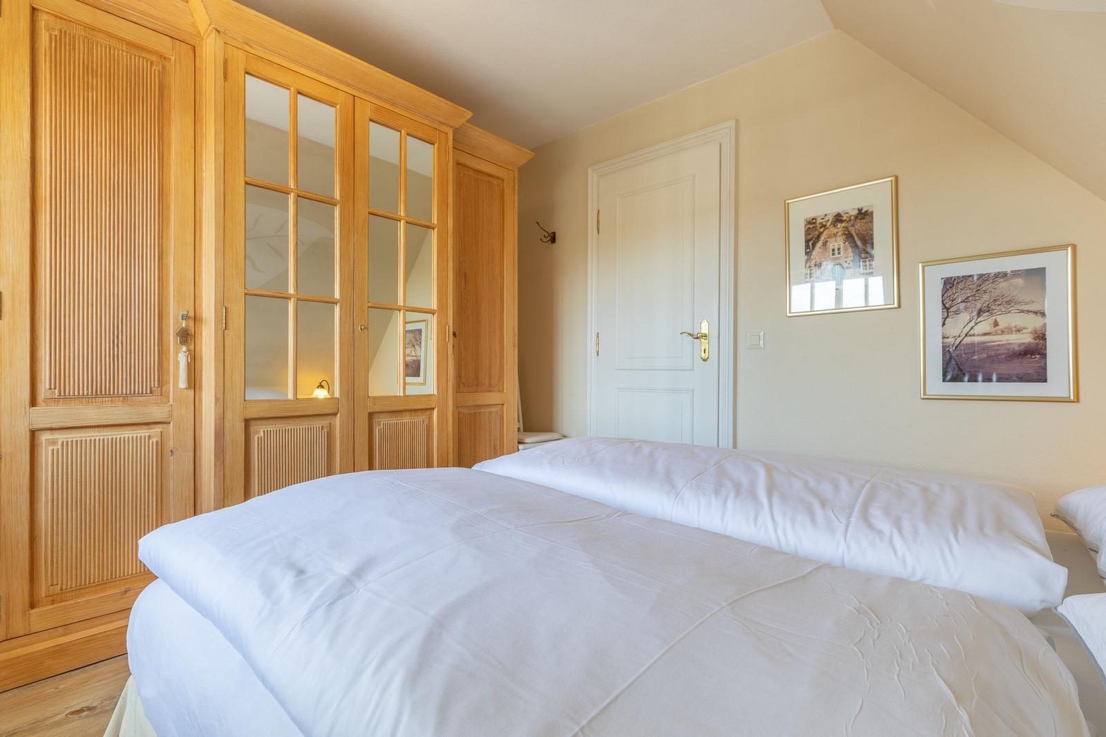 Bedroom with double bed, wooden wardrobe, and two pictures on the wall.