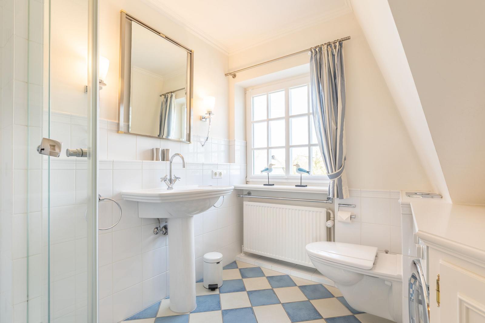 Bathroom with shower, sink and toilet under sloped ceiling.
