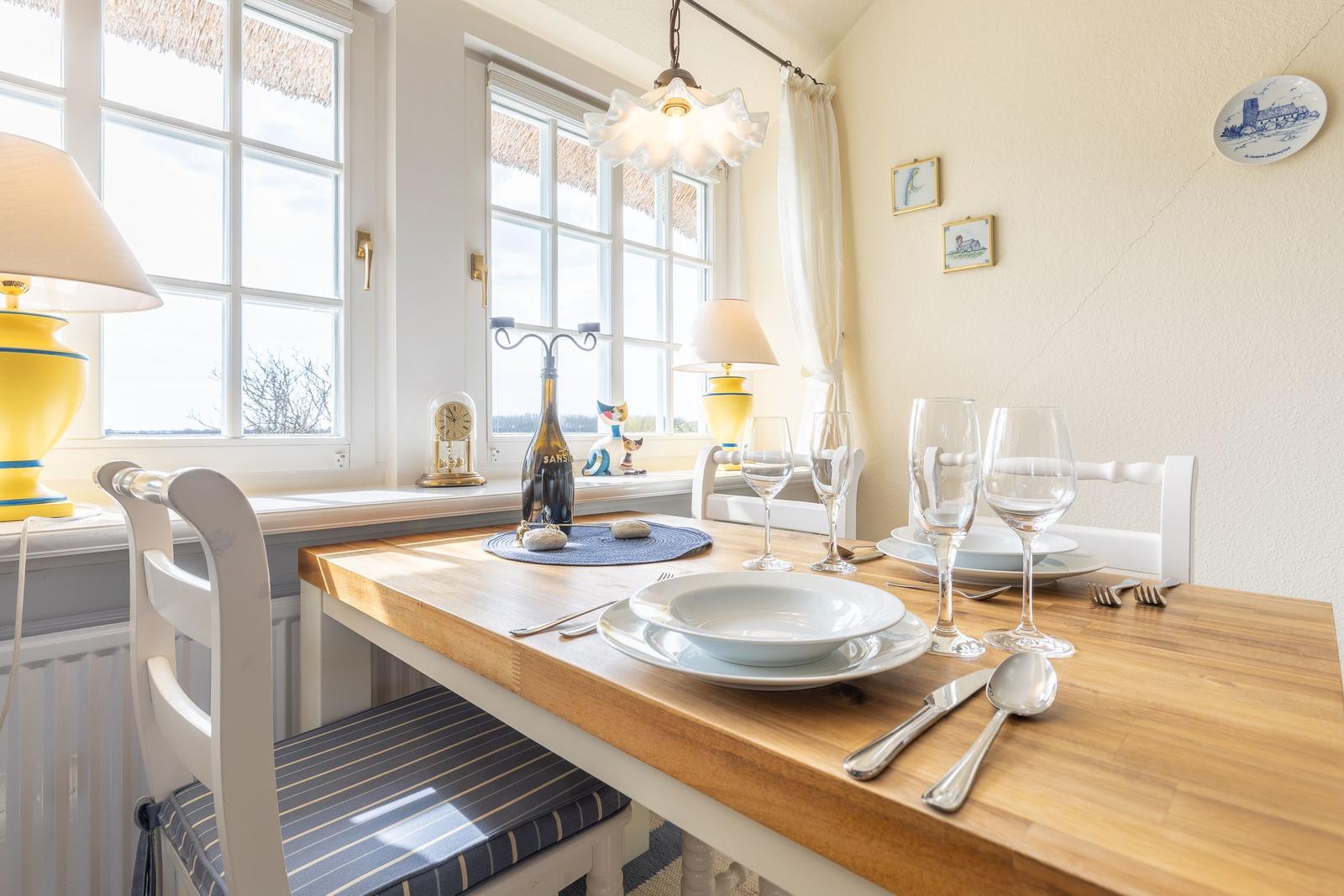 Dining room with wooden table, white chairs, and windows with view outside.