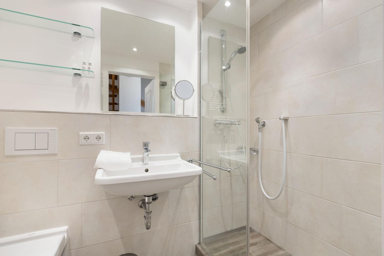 Bad mit Dusche, Waschbecken und Spiegel