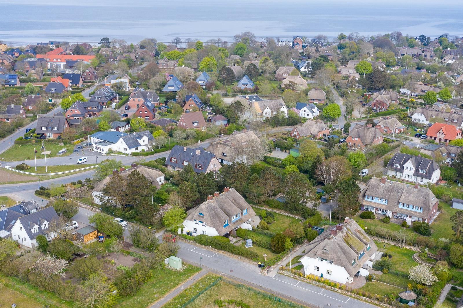 Aerial view of a coastal village with traditional houses and greenery.