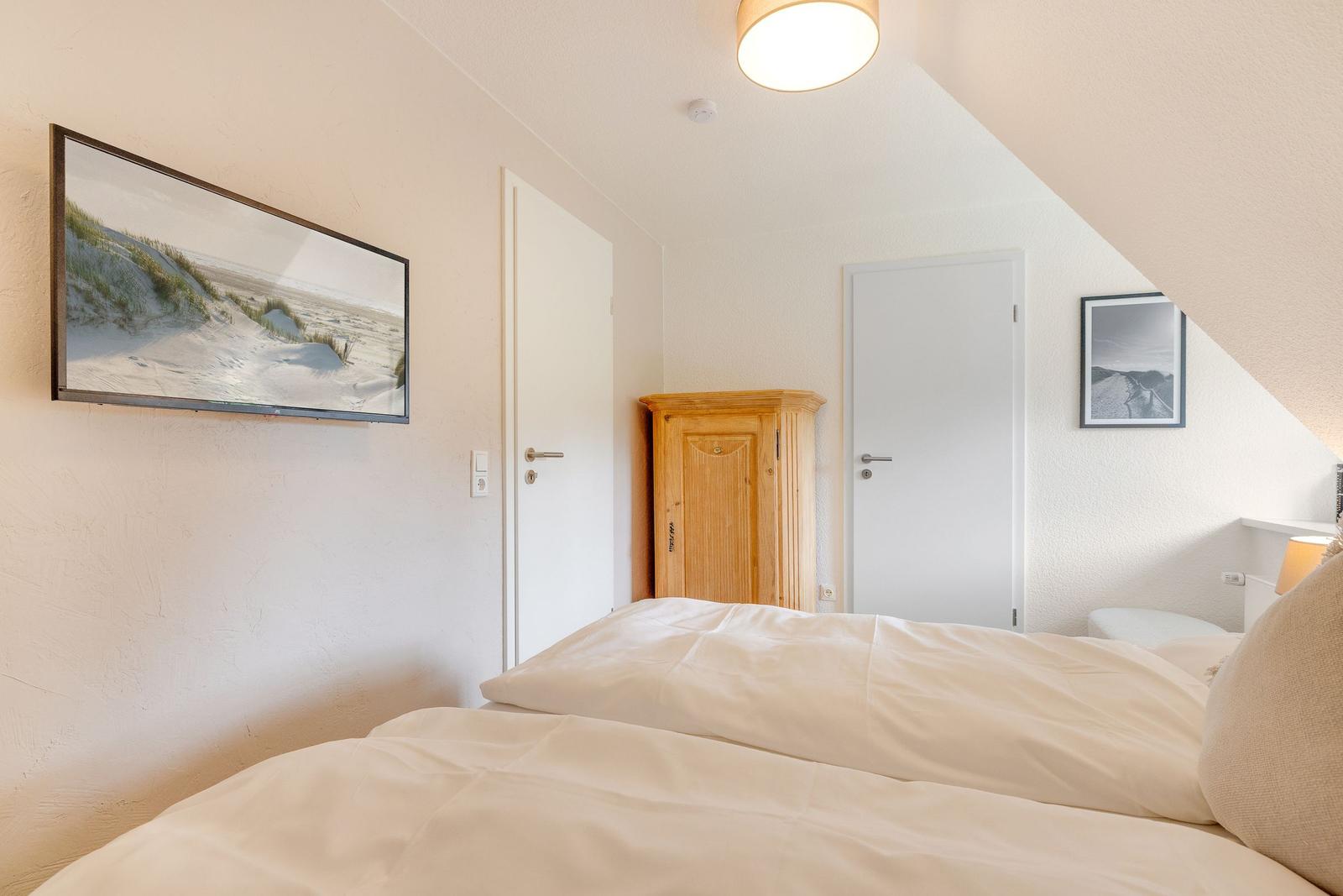 Schlafzimmer mit Bett, Kleiderschrank und Wandbildern