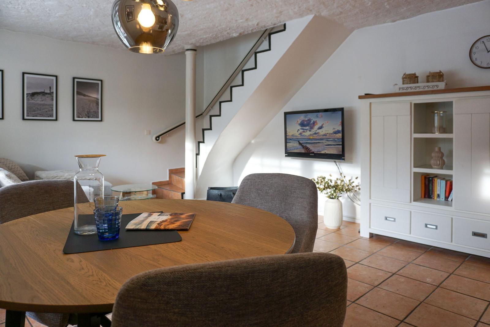 Esszimmer mit runder Tisch, Stühlen und Treppenaufgang.