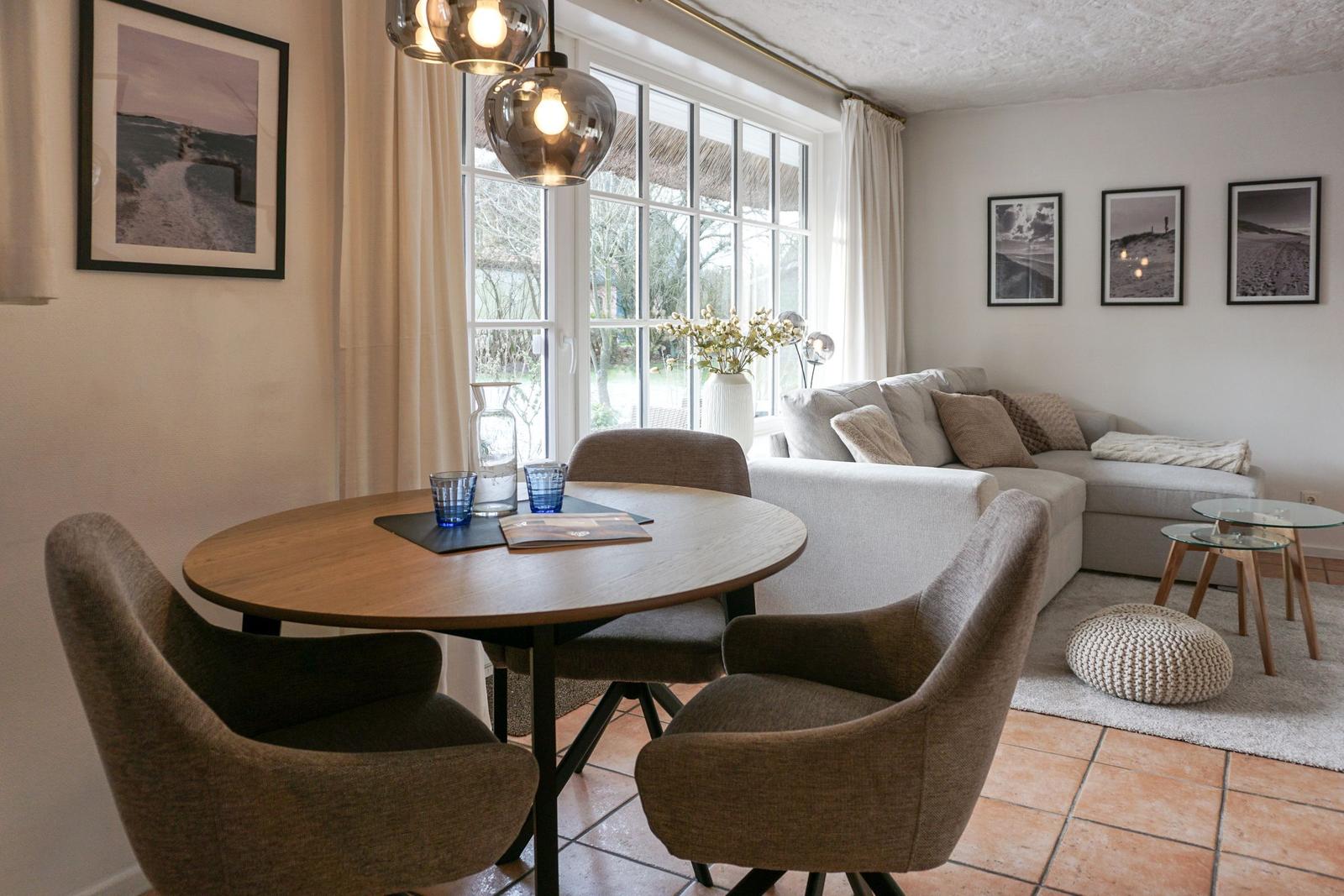 Essbereich mit runder Tisch und Stühlen, Wohnbereich mit Sofa und Fenster.