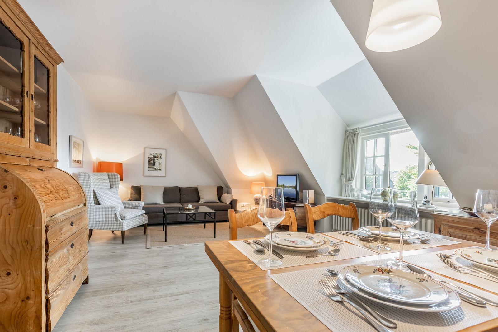 Essbereich mit Tisch und Stühlen. Wohnbereich mit Sofa und Kamin. Holzmöbel und Fenster.