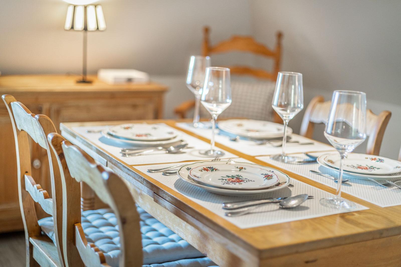 Holztisch mit Platzdeckchen und Geschirr für vier Personen.