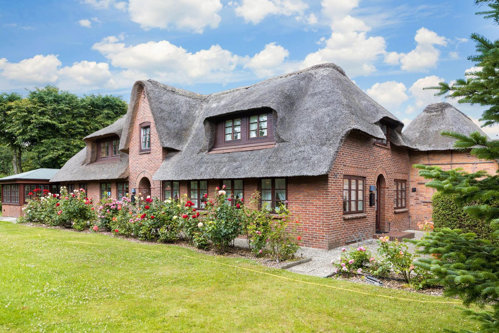 Haus mit Strohdach und Blumenbeet im Vorgarten