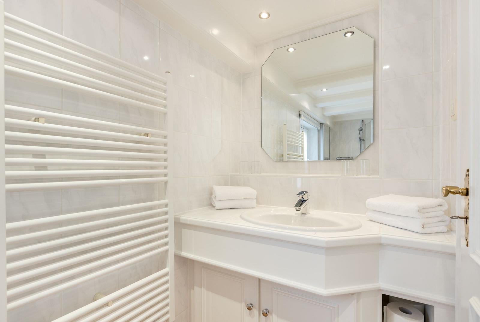 Badezimmer mit Waschbecken, Spiegel und Heizkörper