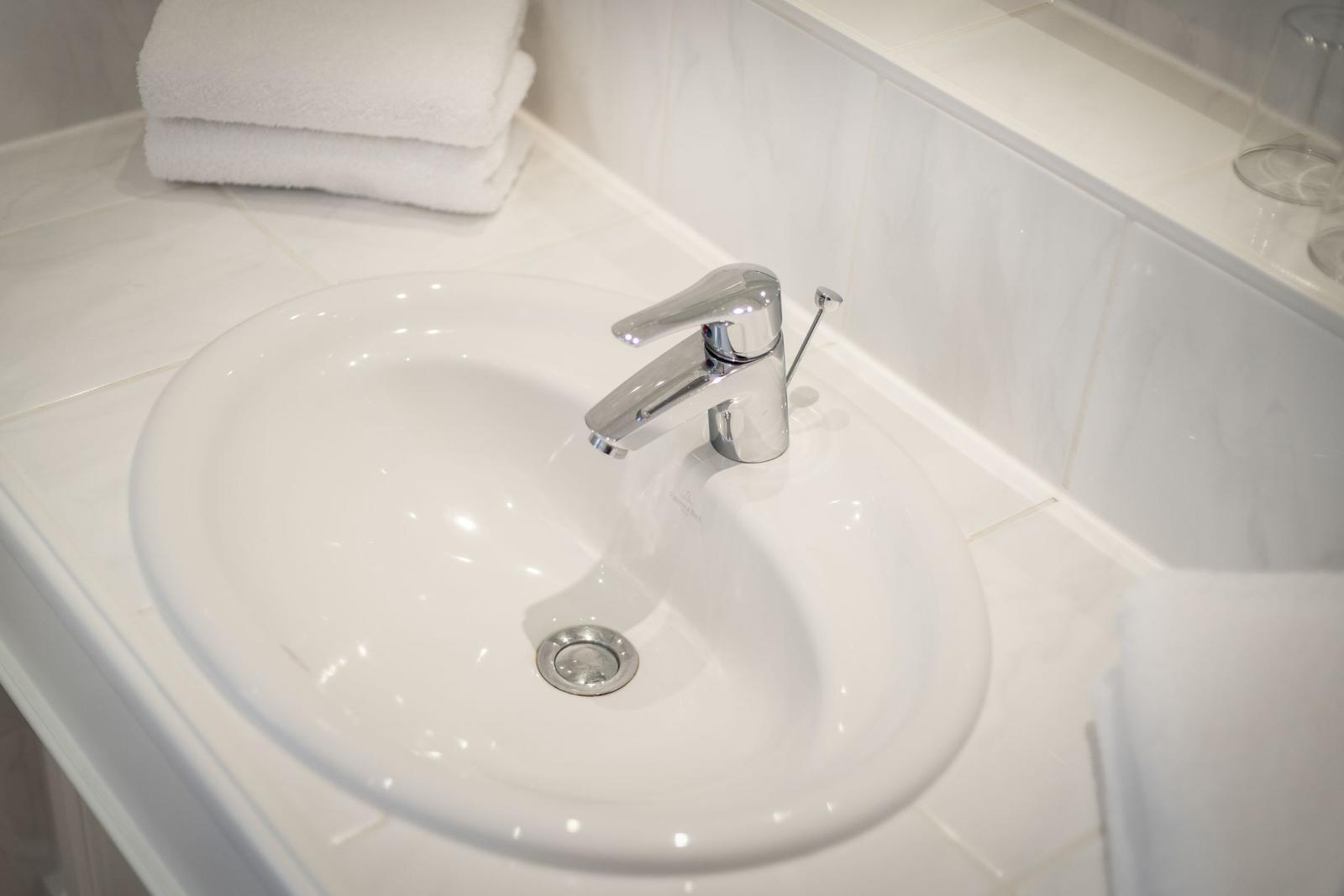 Waschbecken mit Chromhahn auf weißem Waschtisch