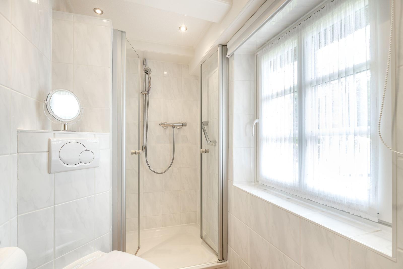 Badezimmer mit Dusche, Fenster und Toilette