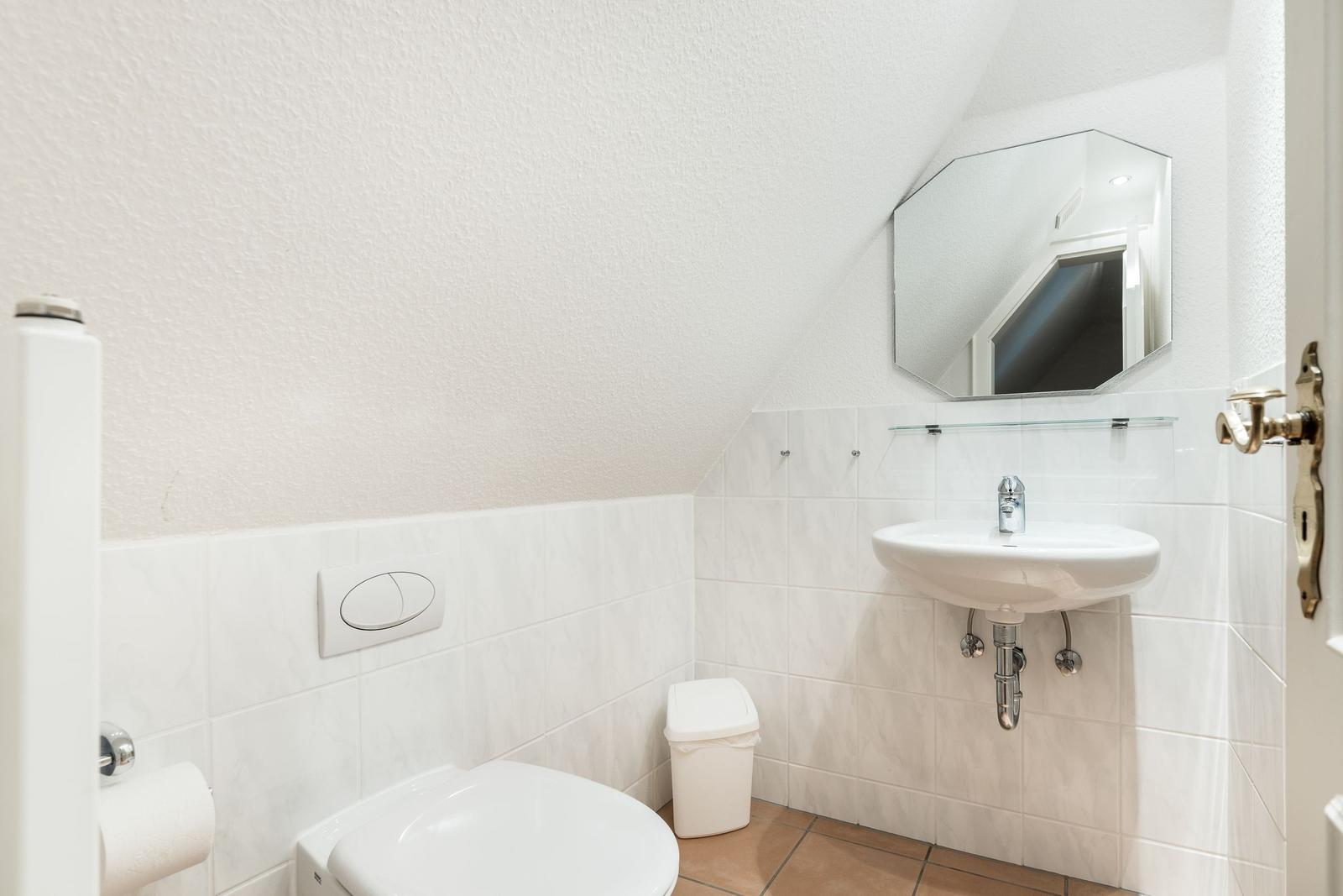 Badezimmer mit Toilette, Waschbecken und Spiegel an der Wand.