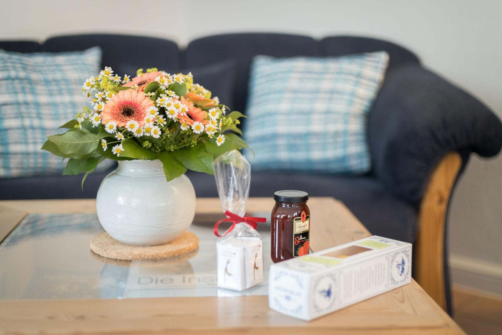 Auf dem Tisch steht eine Blumenvase, ein Glas und Verpackungen.