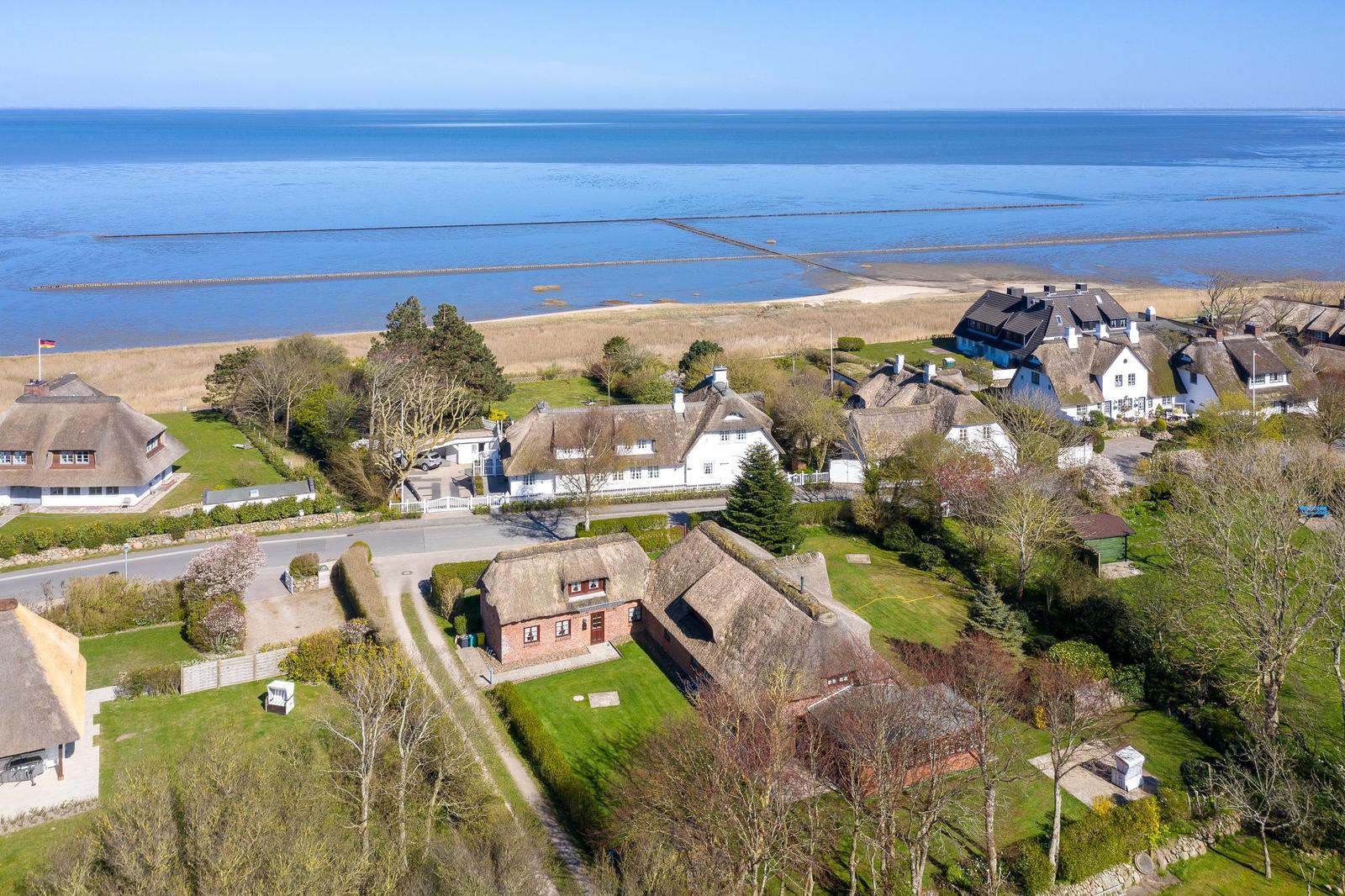 Häuser mit Strohdächern an der Küste mit Blick auf das Meer.