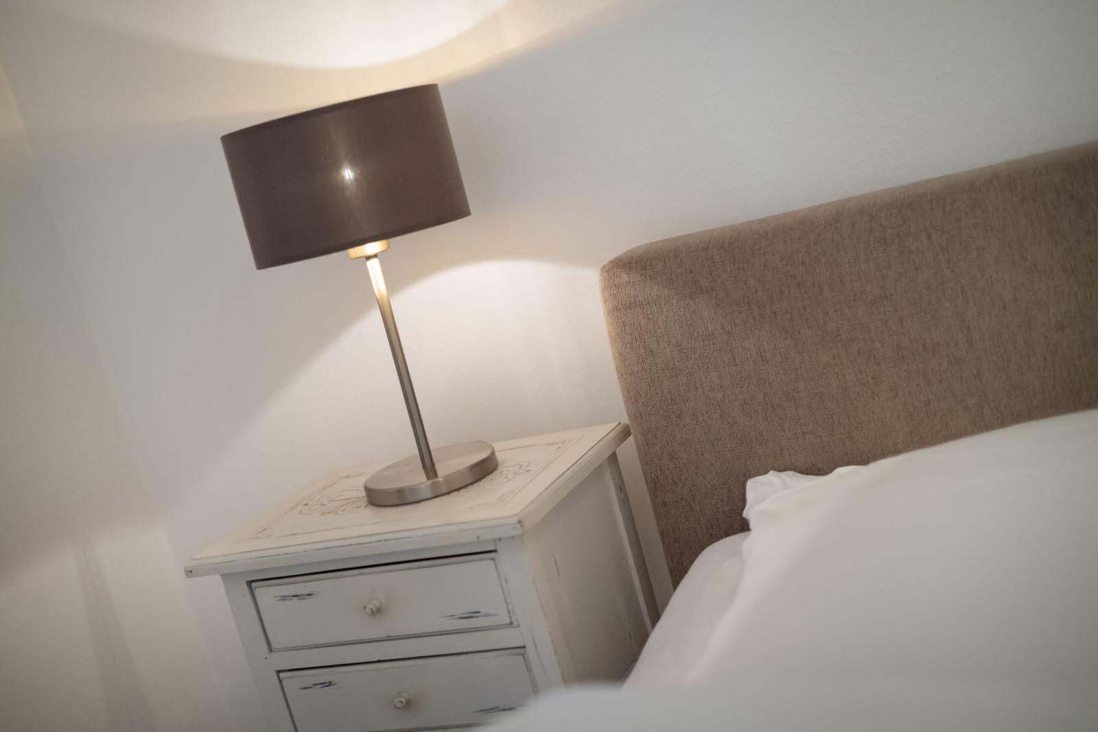 Schlafzimmer mit Nachttisch und Lampe neben dem Bett