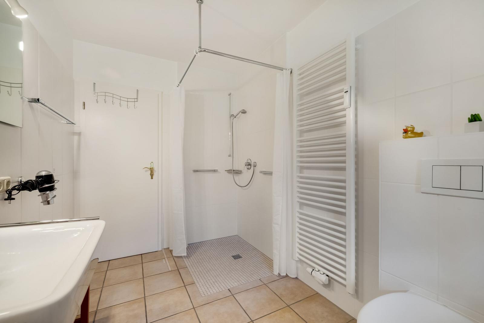 Badezimmer mit Dusche, Waschbecken und Heizkörper
