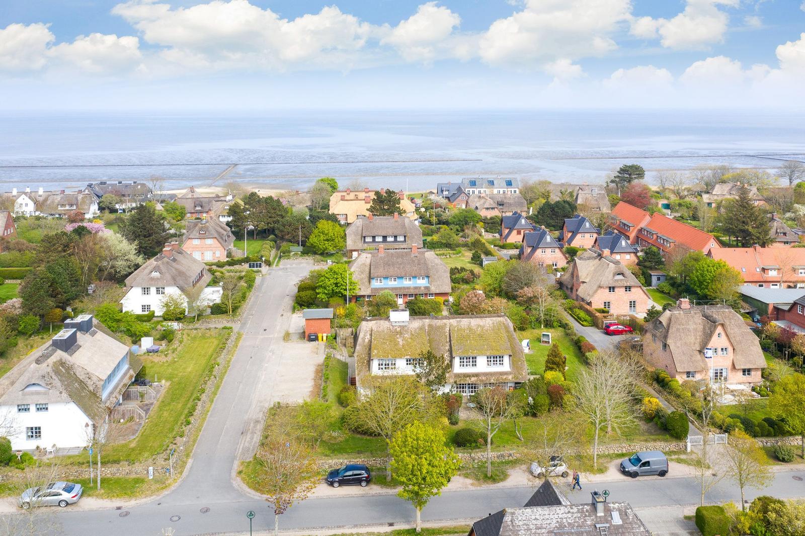 Dorf mit strohgedeckten Häusern und Blick auf die Nordsee.
