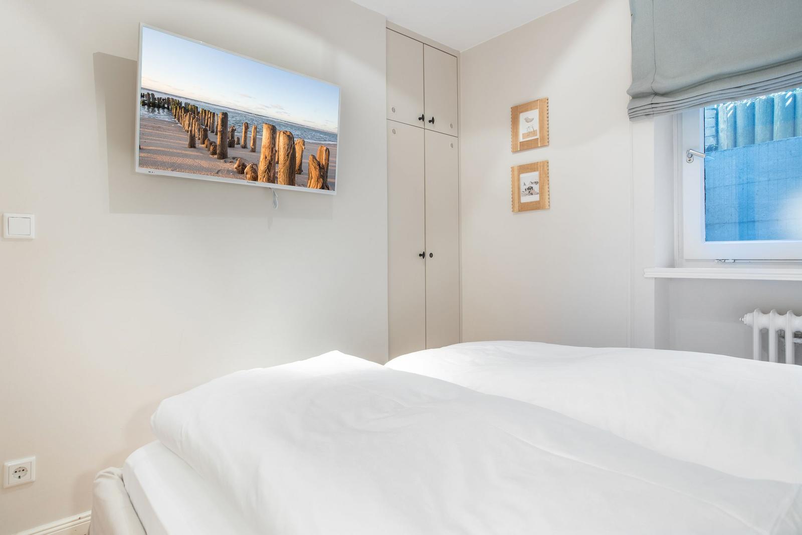 Schlafzimmer mit Bett, TV und Kleiderschrank