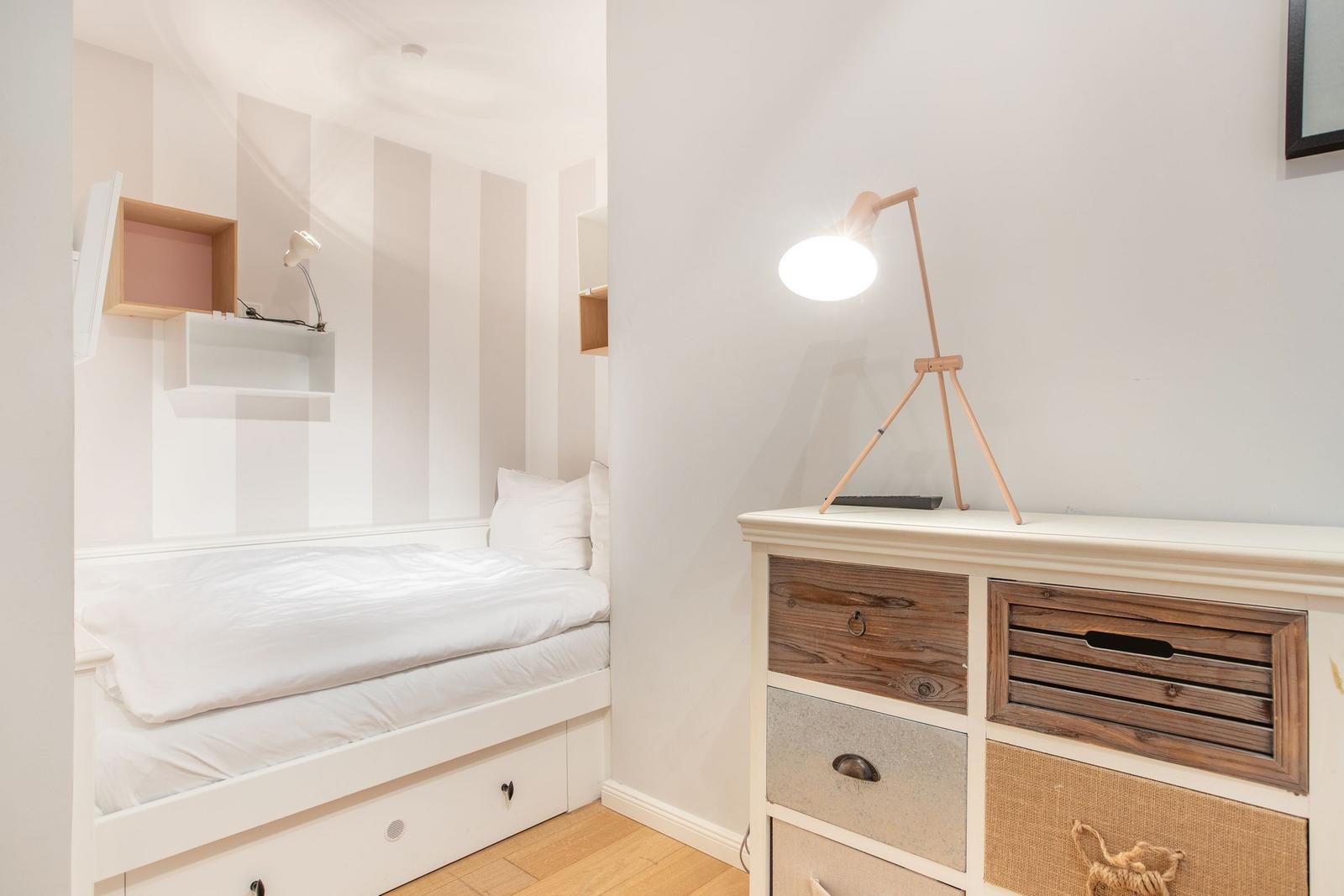 Schlafzimmer mit Bett, Schrank und Stehlampe.