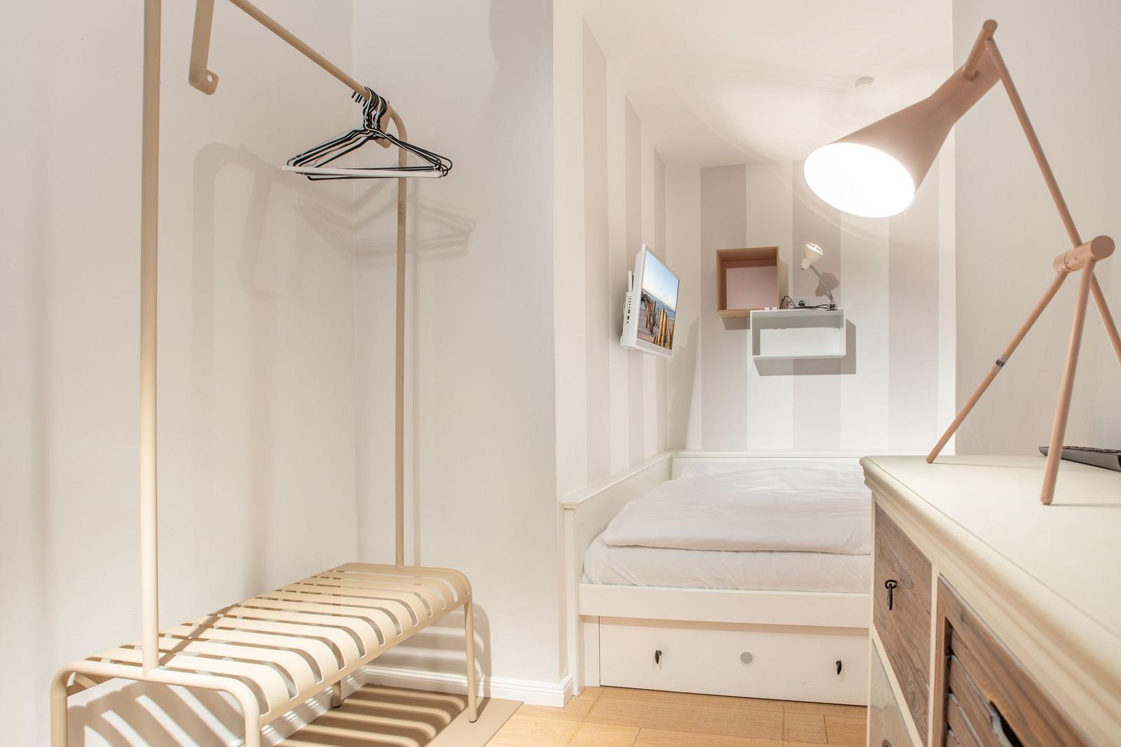 Schlafzimmer mit Bett, Kleiderständer und Schreibtisch