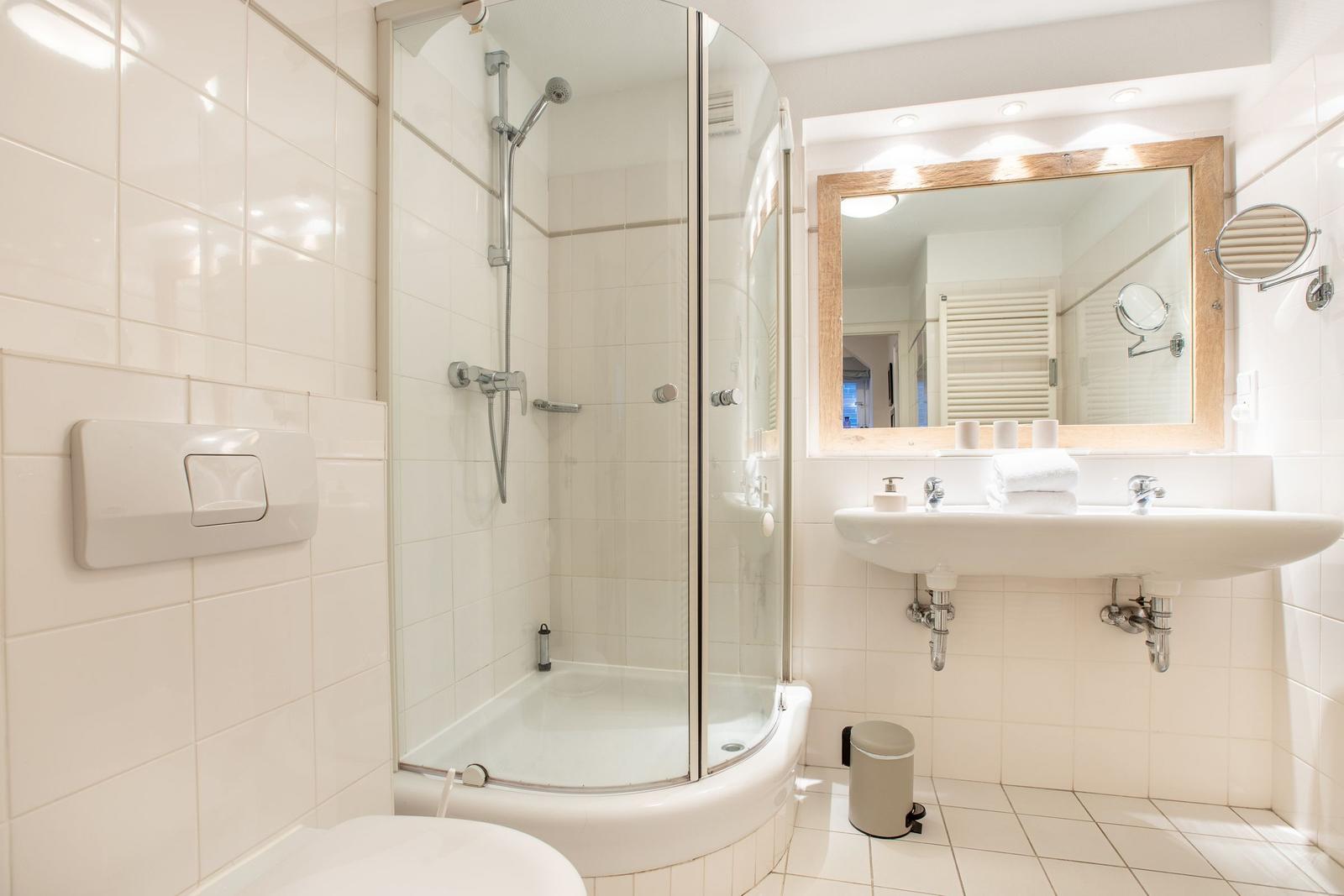 Badezimmer mit Dusche, Waschbecken und Spiegel.