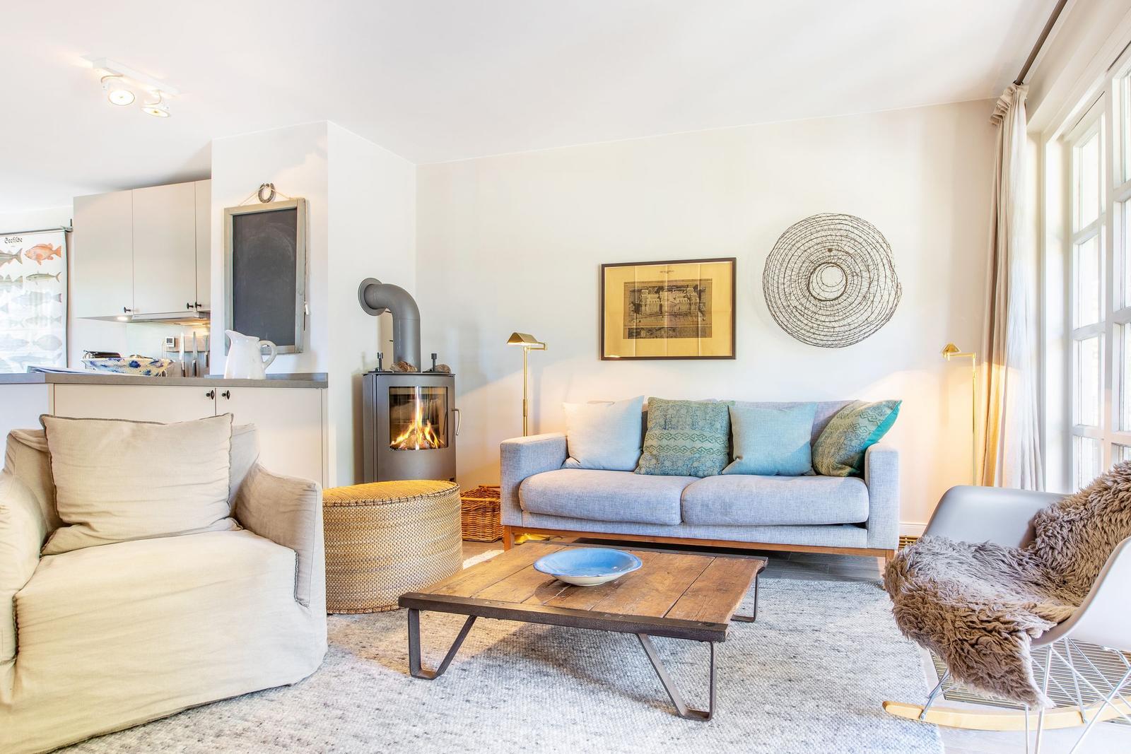 Wohnzimmer mit Sofa, Kamin und Essbereich. Holztisch, Sessel und Wanddekoration.
