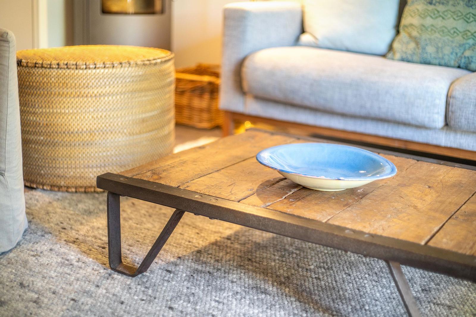 Holztisch mit blauer Schale, Sofa und Korb im Wohnbereich.