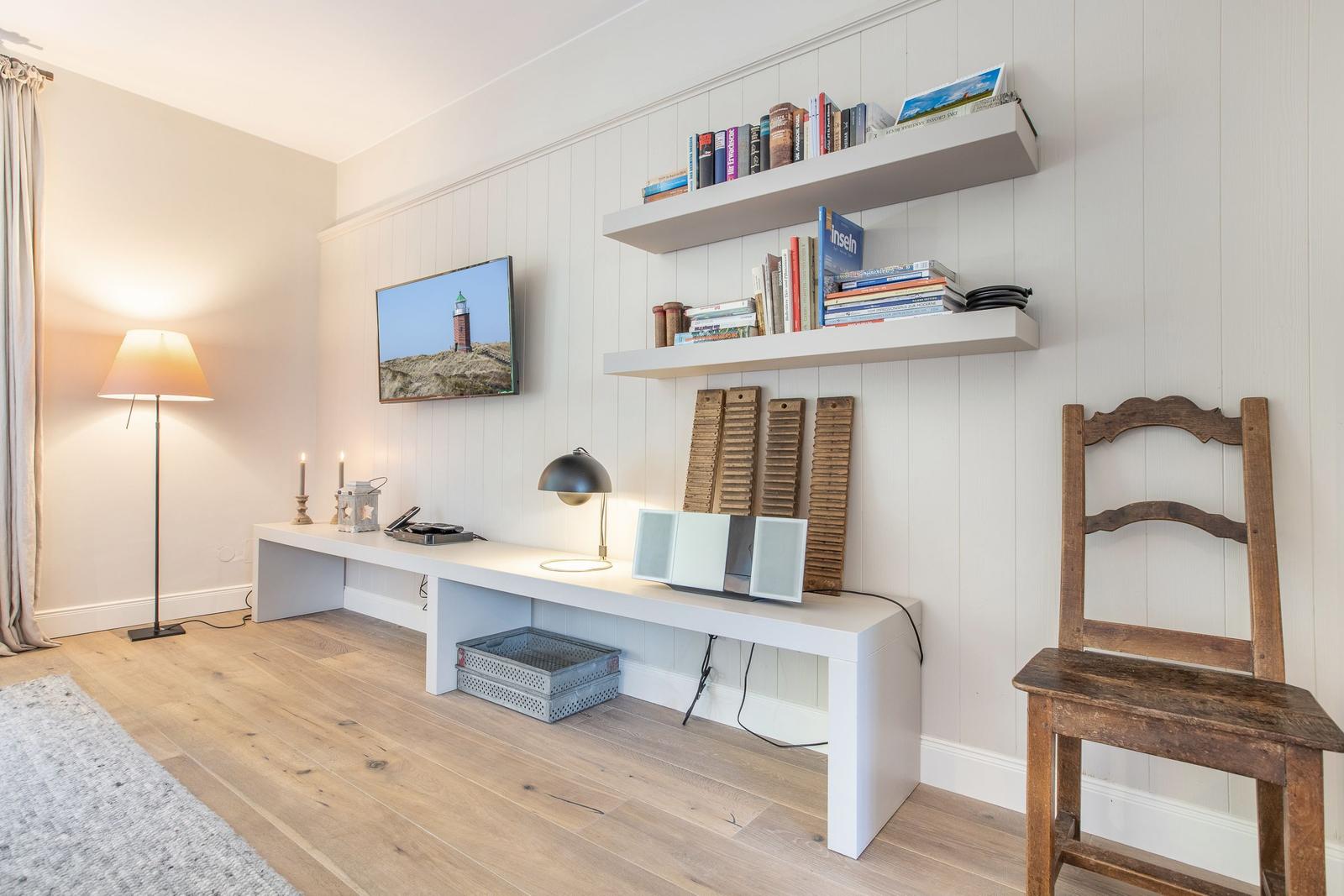Wohnraum mit Schreibtisch, Bücherregal und Fernseher an der Wand.