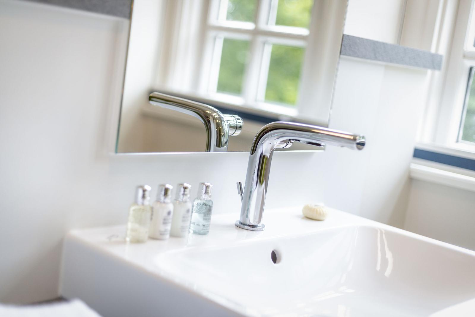Waschbecken mit Spiegel und Fenster im Badezimmer