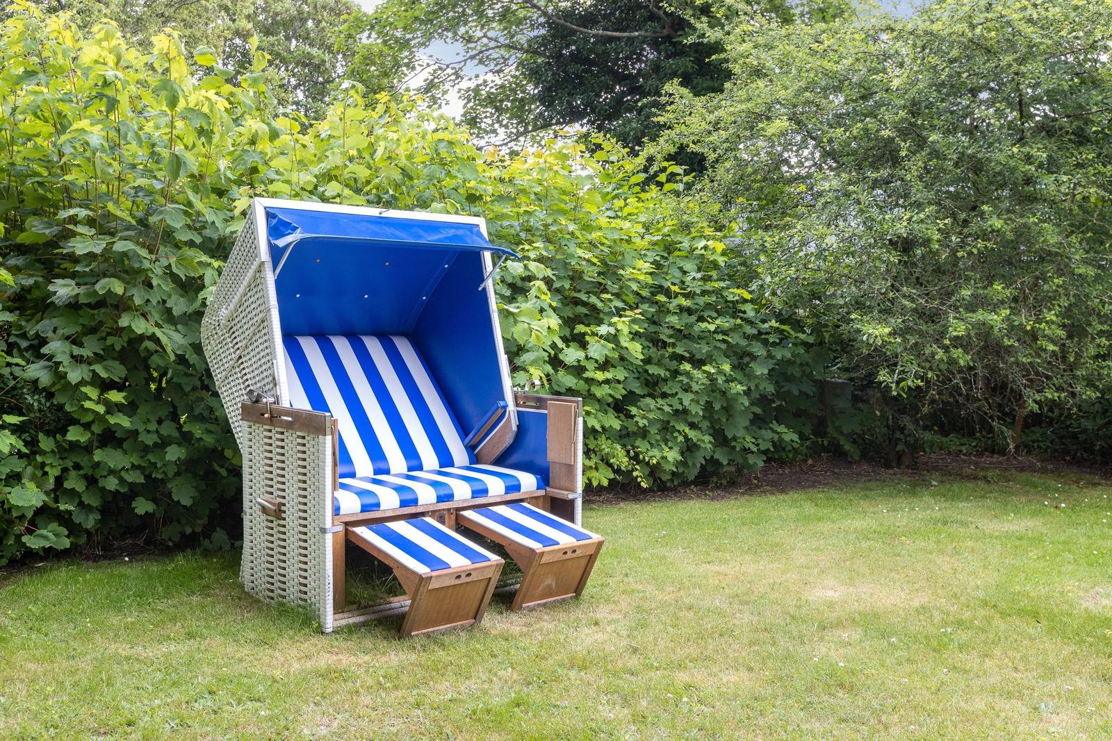 Blau-weiße Strandliege mit Schirm im Garten