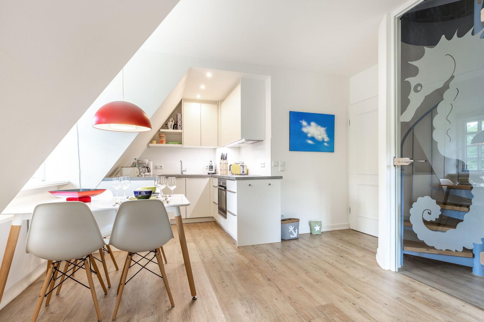 Küche mit Esstisch, roter Lampe und Glaswand mit Seepferdchenmotiv.