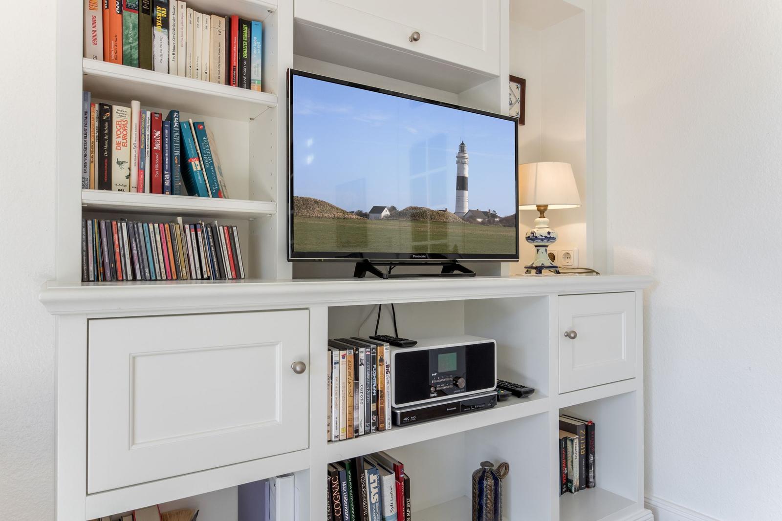 TV on white cabinet with bookshelves and lamp.