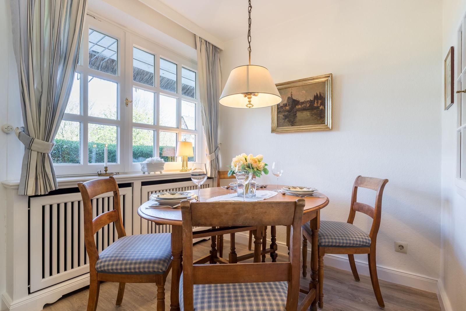 Dining room with wooden table, four chairs, and garden view.