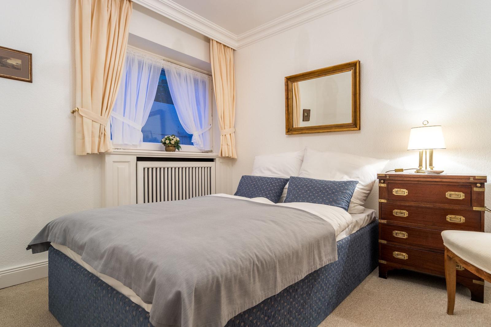 Bedroom with bed, nightstand, and window with curtains.
