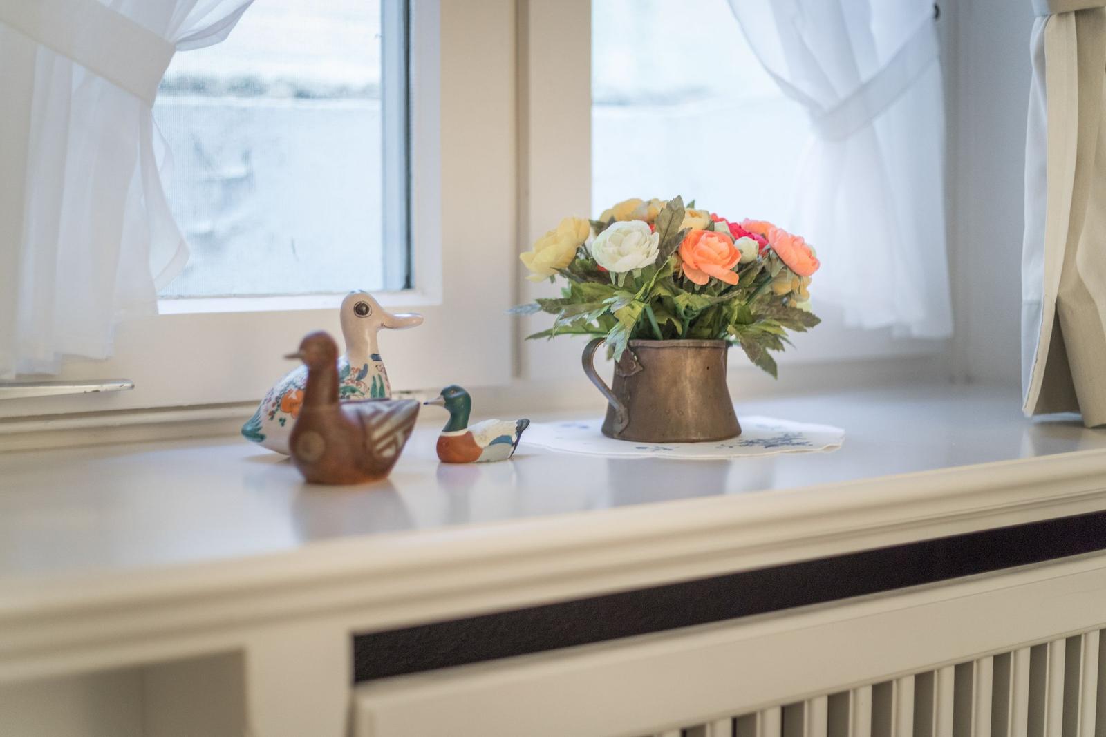 Three duck figurines and a flower vase are on the windowsill.