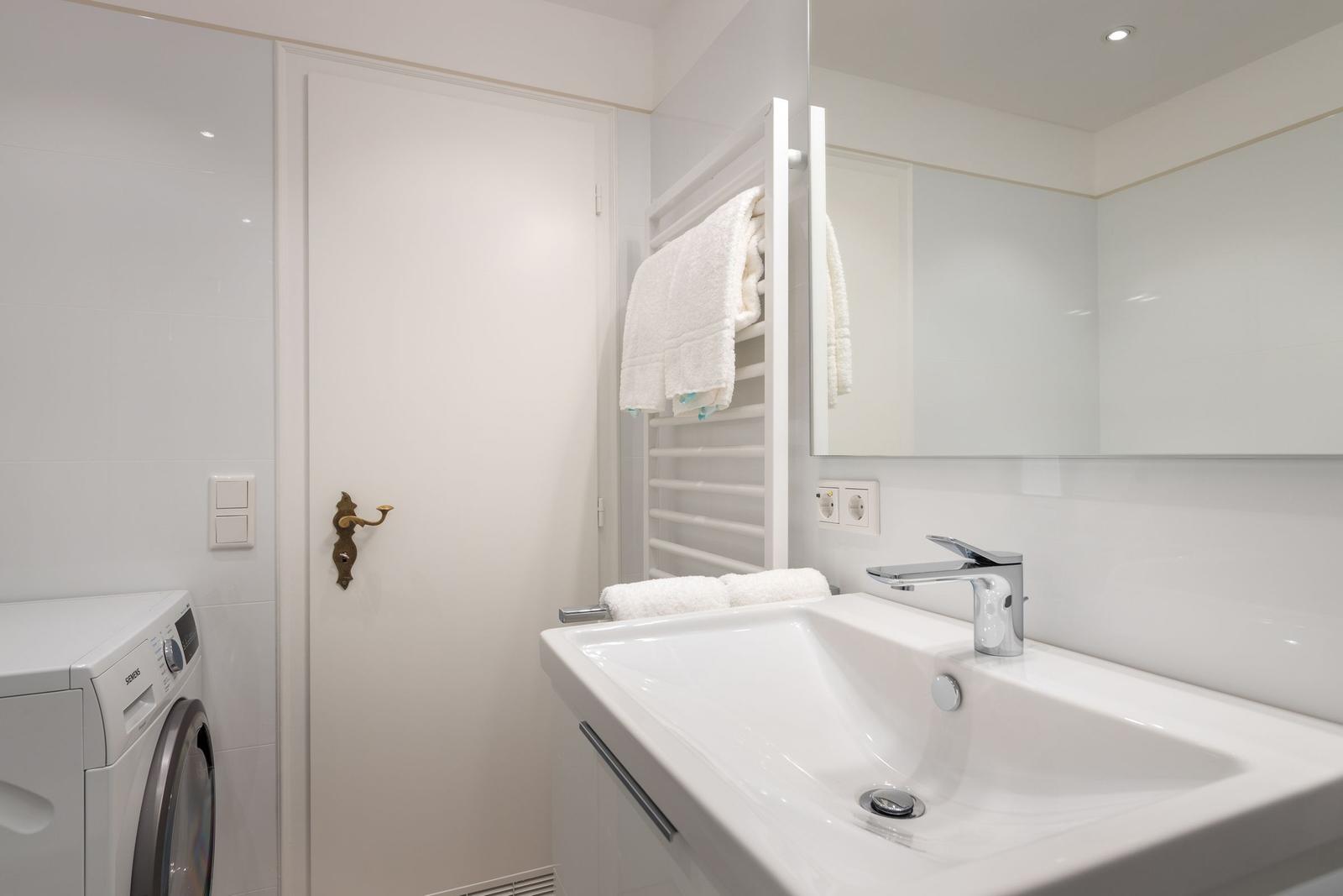 Bathroom with washing machine, mirror, and towel rack.