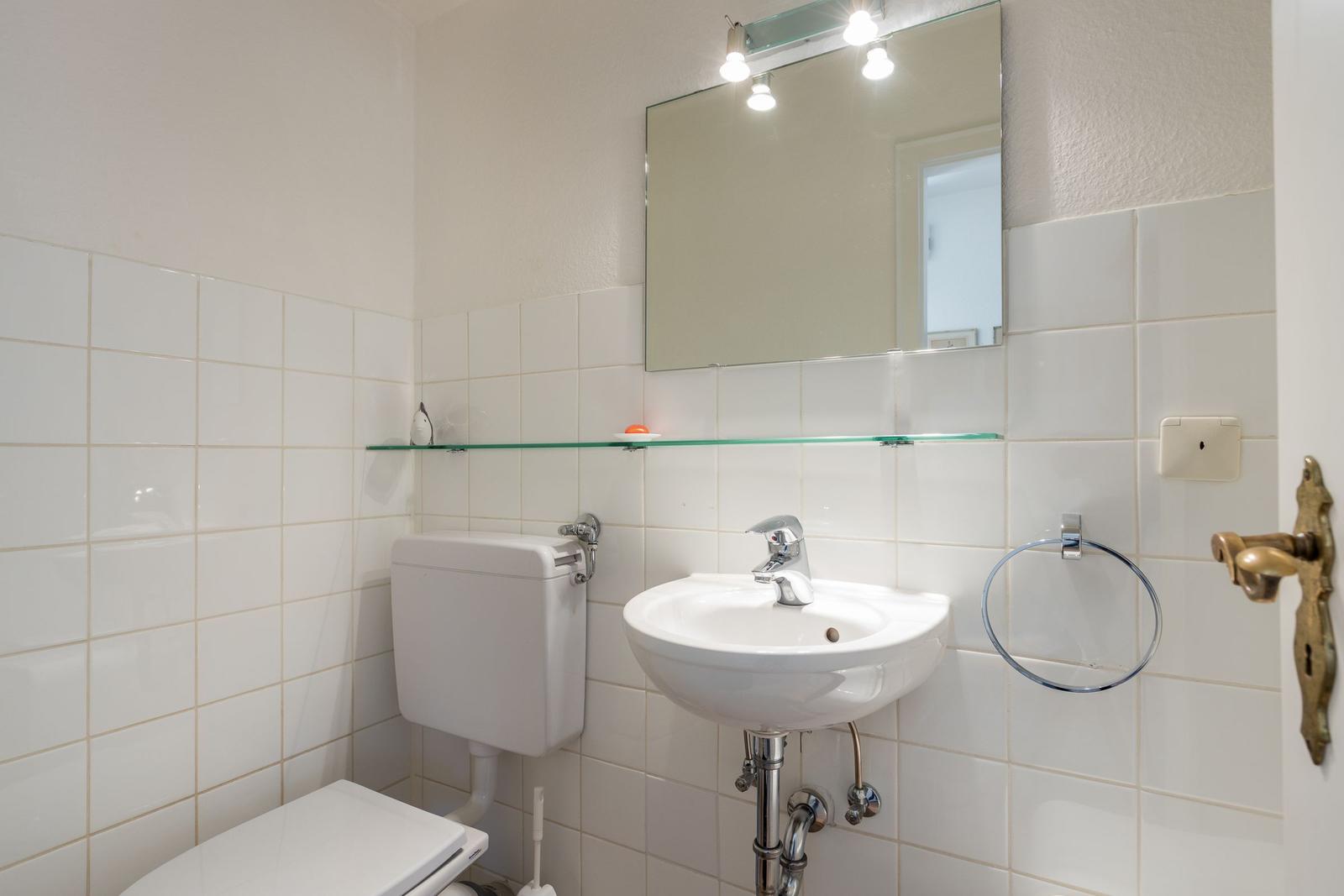 Bathroom with toilet, sink, and mirror.