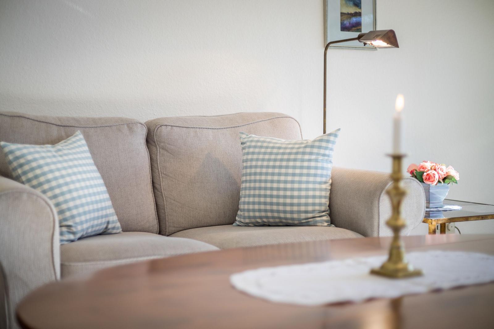 A sofa with cushions, a floor lamp, and a table lamp with a candle.