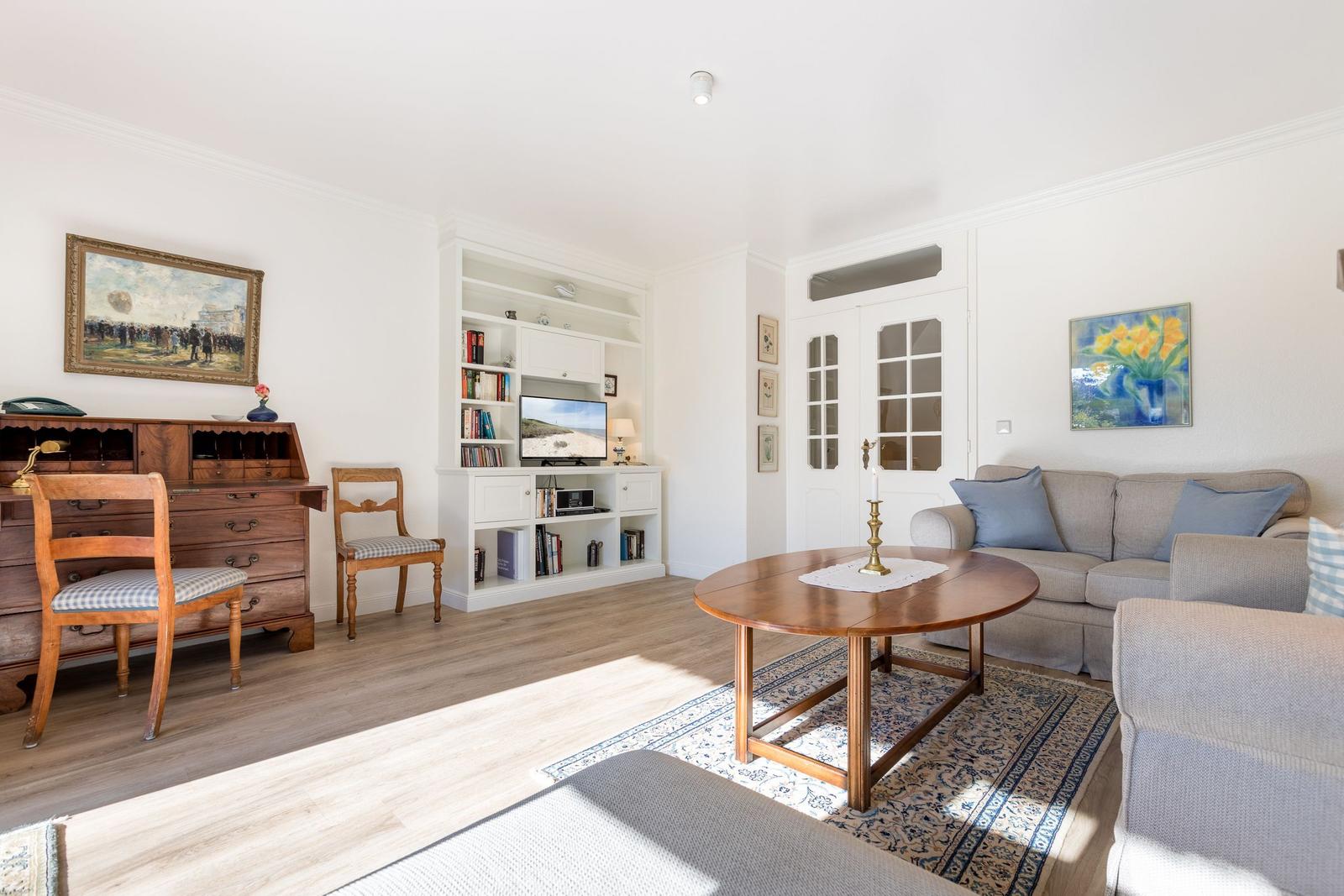 Living room with sofa, wooden table, bookcase, and TV.