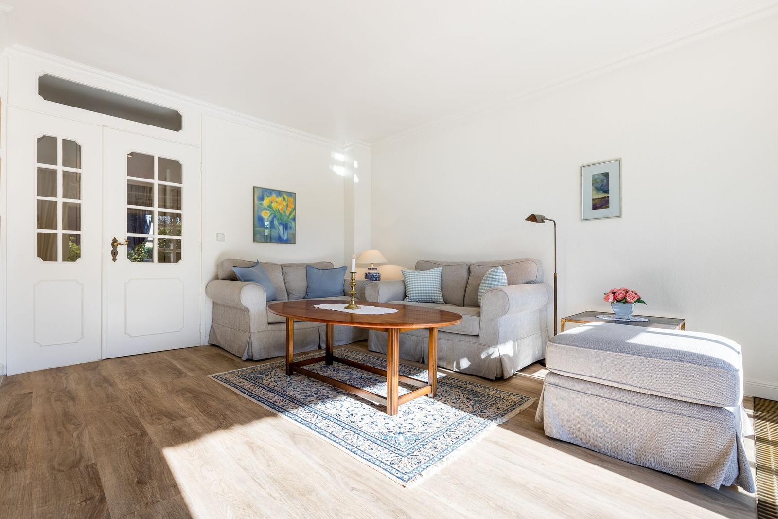 Living room with sofa, table, and rug. Windows and door are visible.