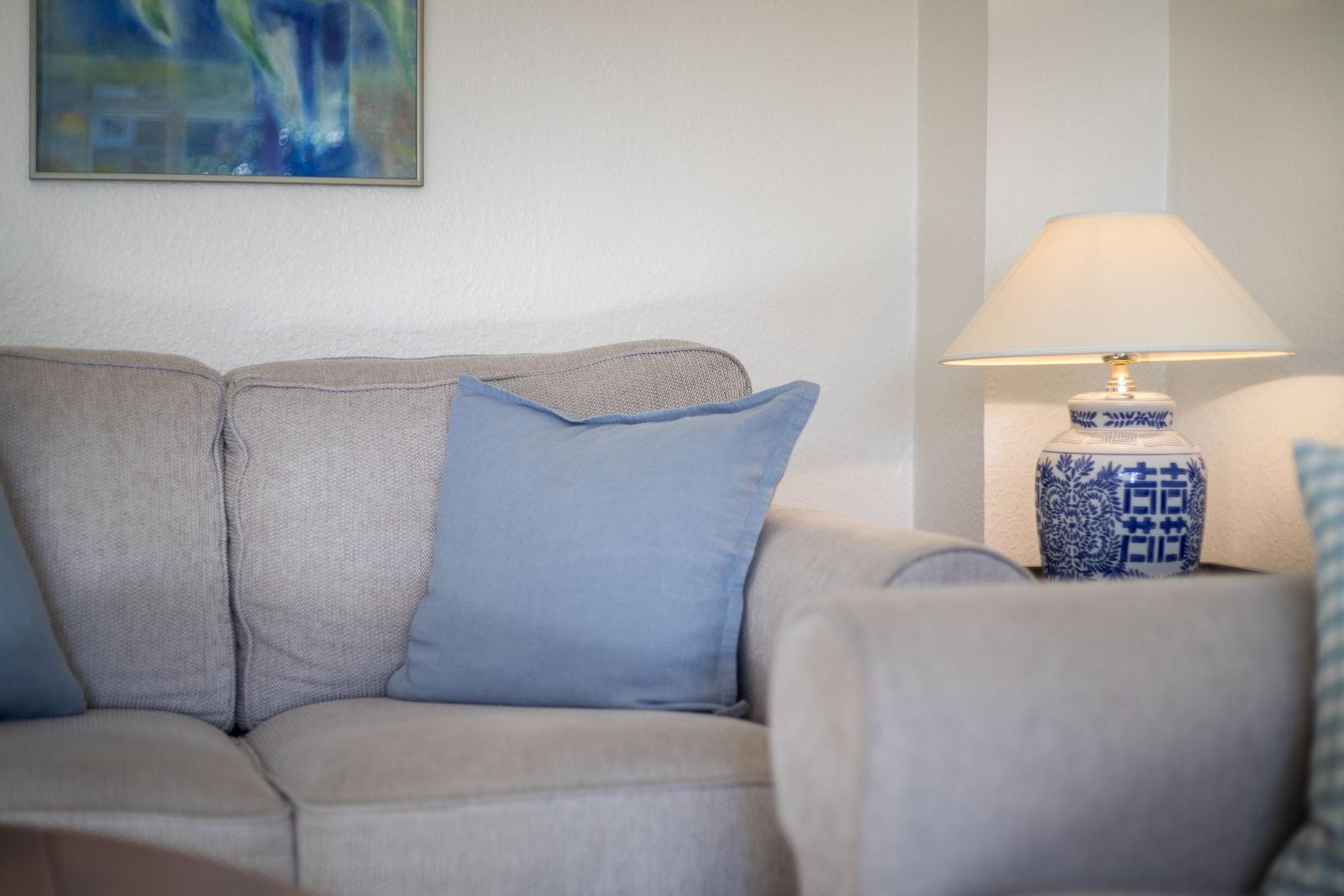 Gray sofa with blue pillow and lamp with blue-white pattern.