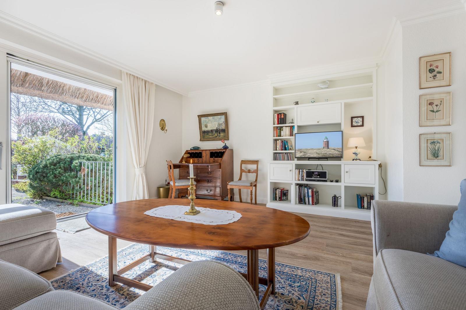 Living room with dining table, TV, and view to balcony.
