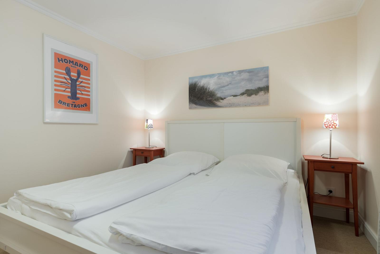 Bedroom with bed, two nightstands, and wall pictures.