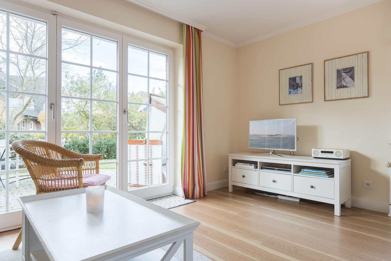 Living room with TV, coffee table, and glass doors to the garden.