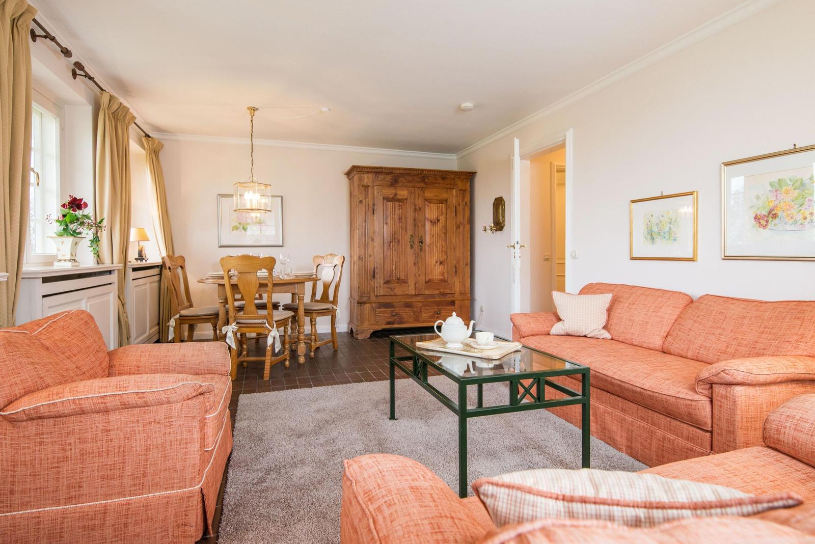 Wohnzimmer mit Sofa, Couchtisch und Essbereich. Holzmöbel und Bilder an den Wänden.