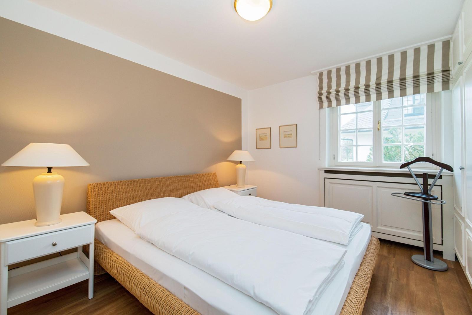 Schlafzimmer mit Doppelbett, Nachttischen und Fenster mit Markise.