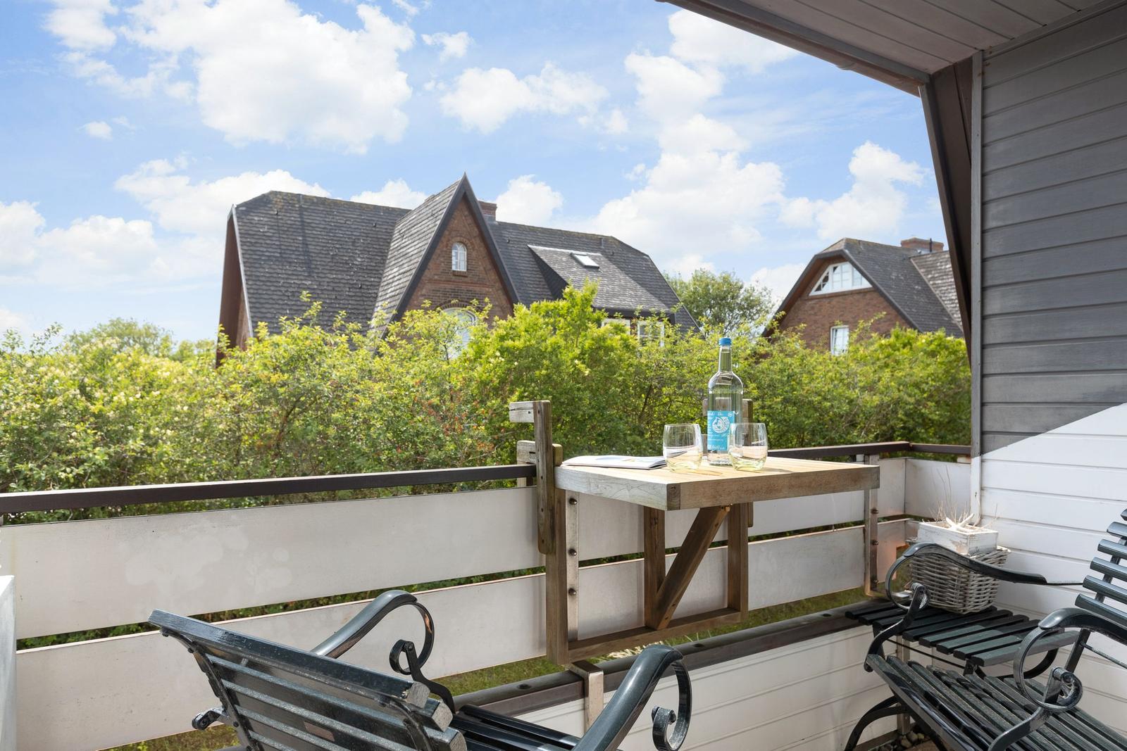 Terrasse mit Tisch, Stühlen und Blick auf Häuser und Bäume.