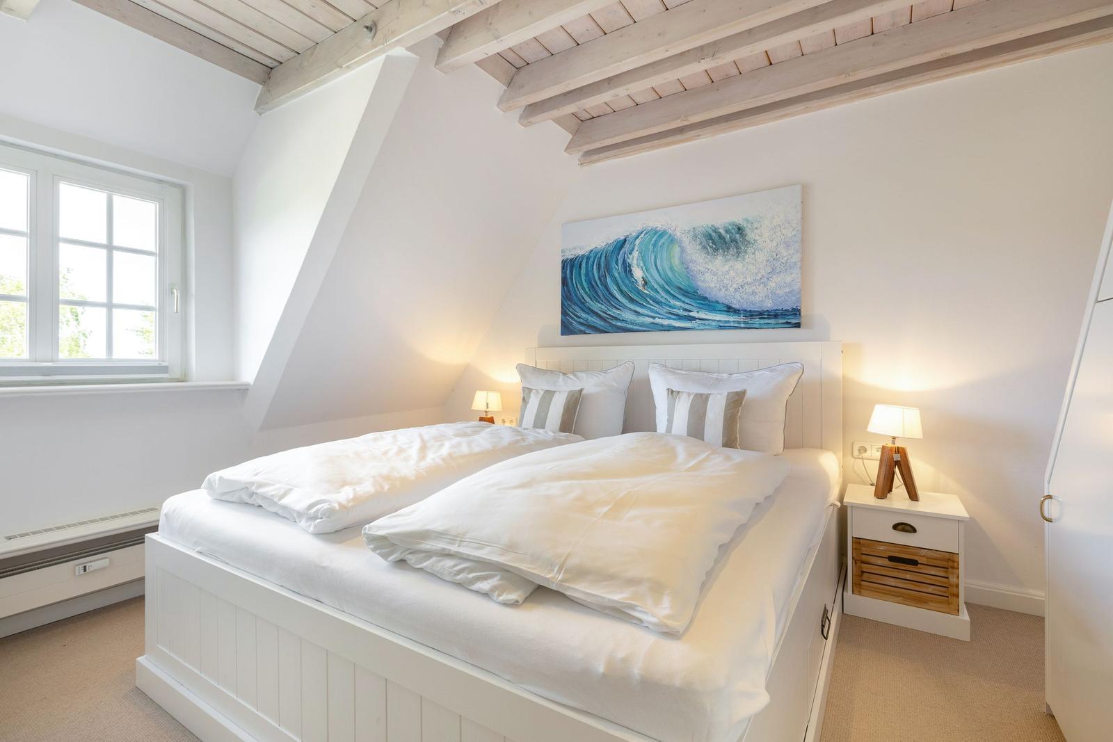 Schlafzimmer mit Doppelbett, Wandbild und Holzbalken an der Decke.