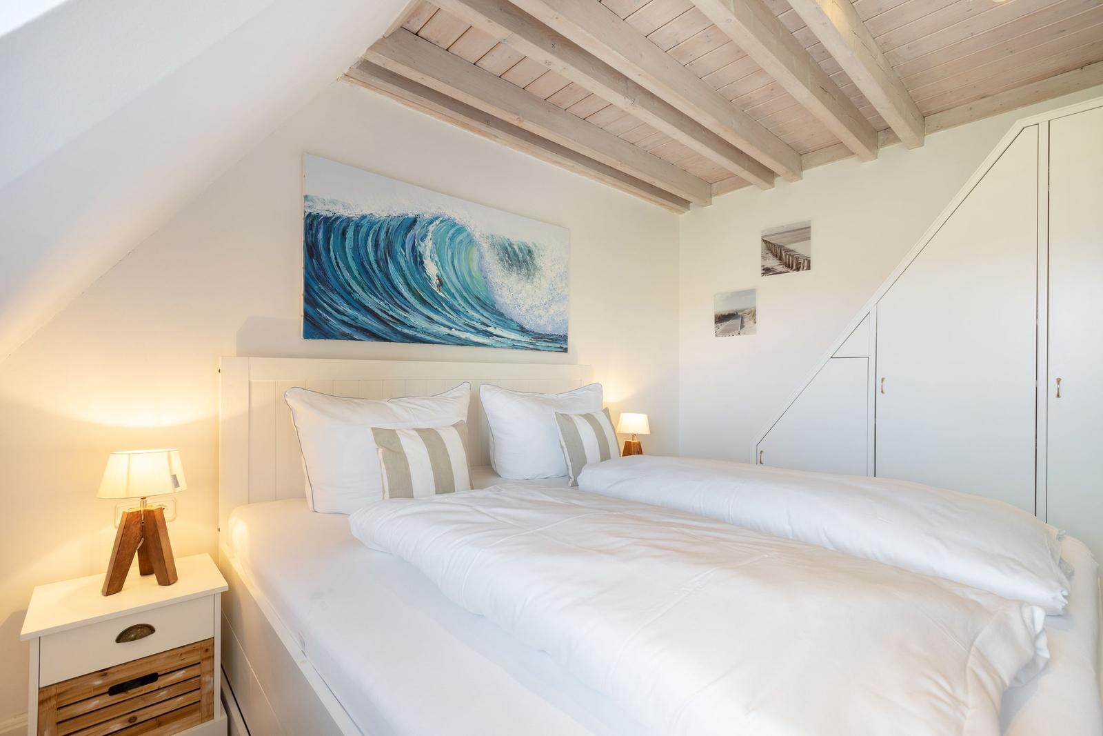 Schlafzimmer mit Doppelbett, Wandbild und Holzbalkendecke.