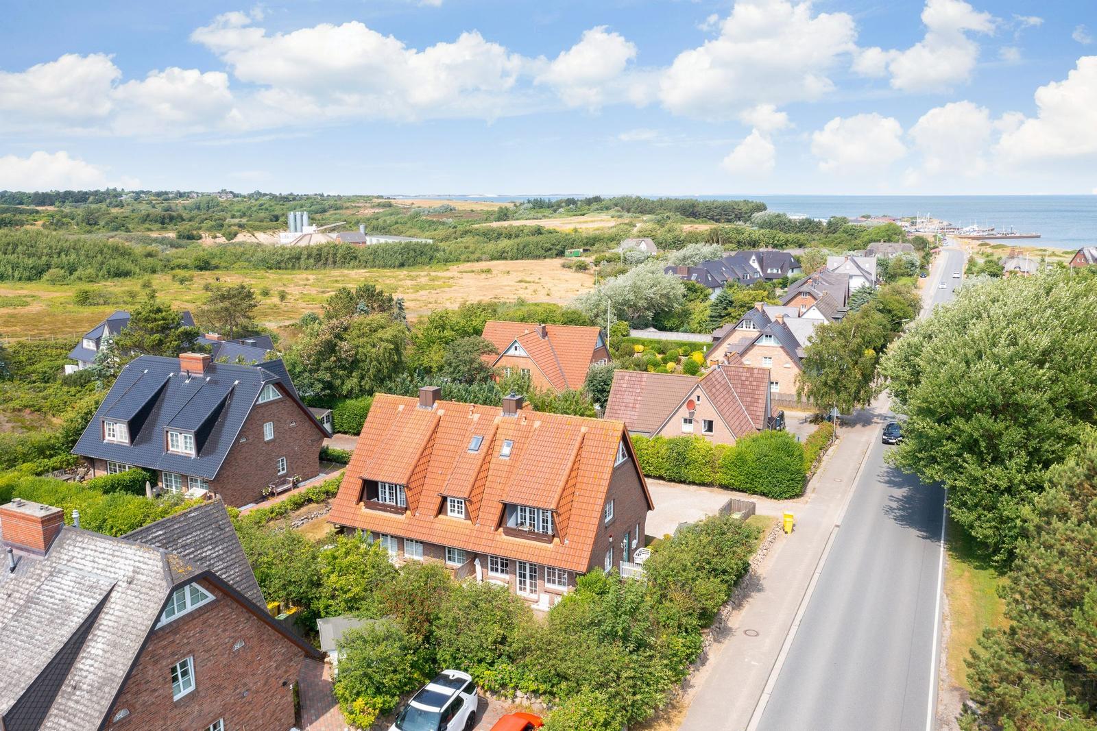 Dorf mit Häusern, Grünflächen und Blick aufs Meer.